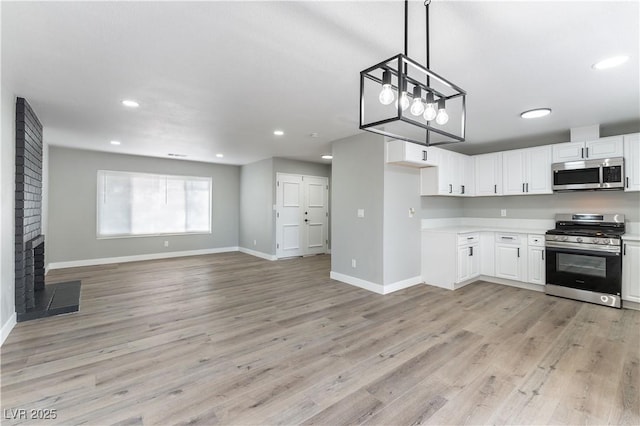 kitchen with stainless steel appliances, light countertops, white cabinets, and baseboards