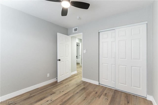 unfurnished bedroom with a closet, visible vents, wood finished floors, and baseboards