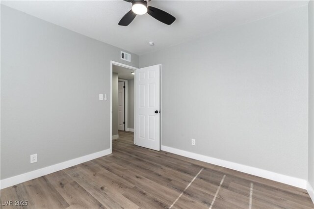 empty room with visible vents, ceiling fan, wood finished floors, and baseboards