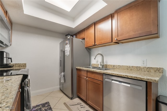 kitchen with a sink, appliances with stainless steel finishes, light tile patterned floors, and brown cabinets