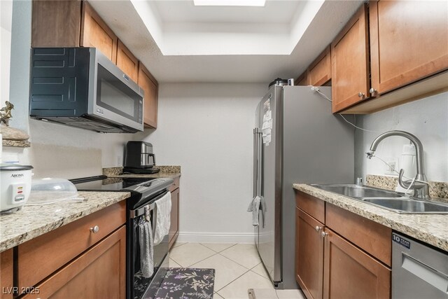 kitchen featuring brown cabinetry, appliances with stainless steel finishes, and a tray ceiling