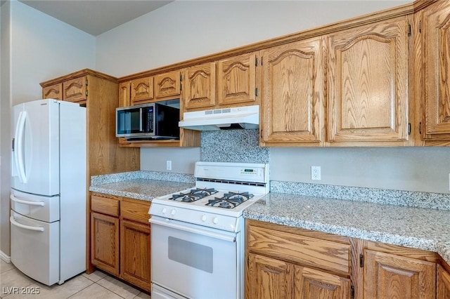 3684 Mooncrest Cir, Las Vegas, NV 89129 - kitchen with white appliances, under cabinet range hood, light tile patterned floors, light stone counters, and brown cabinets