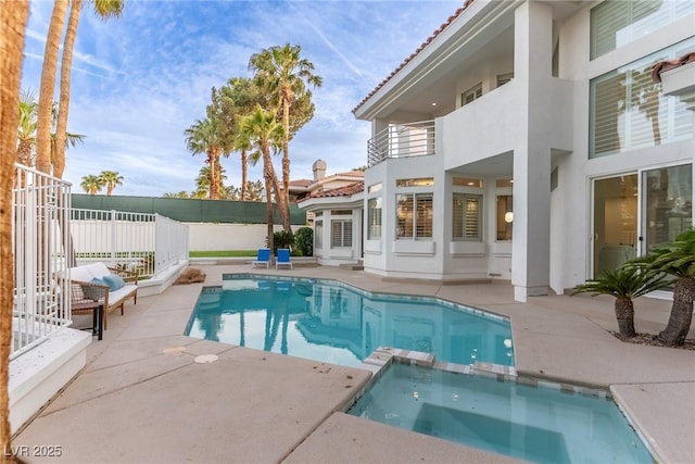 view of swimming pool with a patio, a pool with connected hot tub, and fence