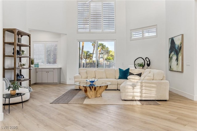 living room with baseboards, a towering ceiling, and wood finished floors