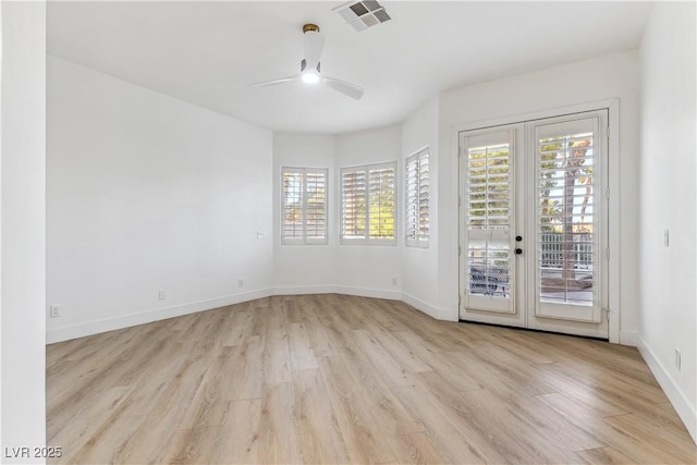 empty room featuring visible vents, a ceiling fan, plenty of natural light, and wood finished floors