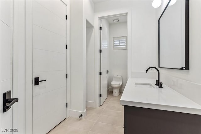 bathroom with toilet, tile patterned floors, baseboards, and vanity