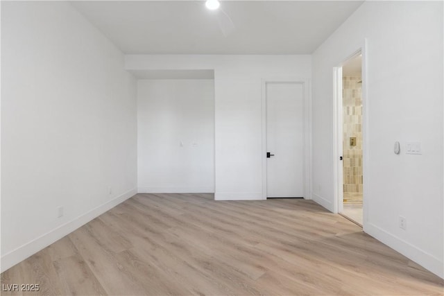spare room with baseboards and light wood-type flooring