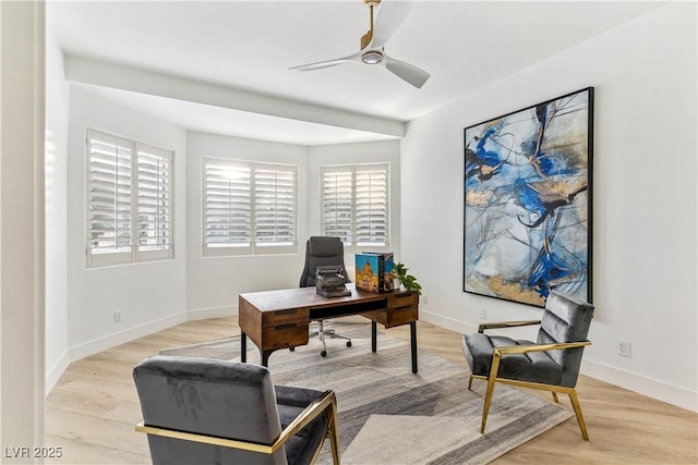 office featuring a ceiling fan, baseboards, and light wood-type flooring