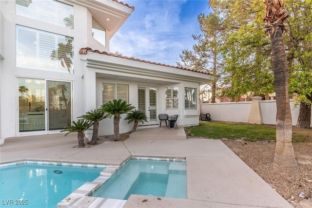 rear view of house with a patio area, stucco siding, a tiled roof, and fence