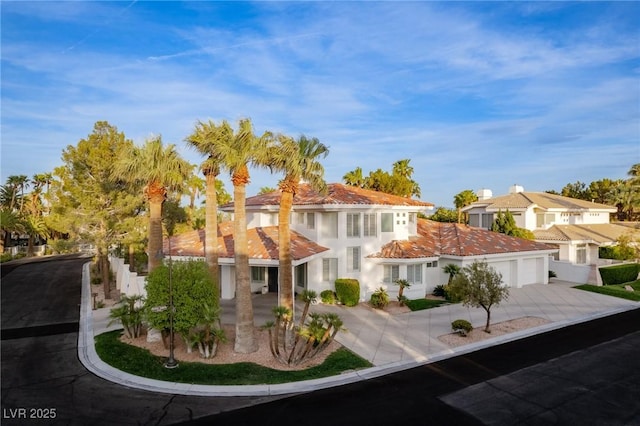 view of front of property featuring a garage, a residential view, driveway, and a tile roof