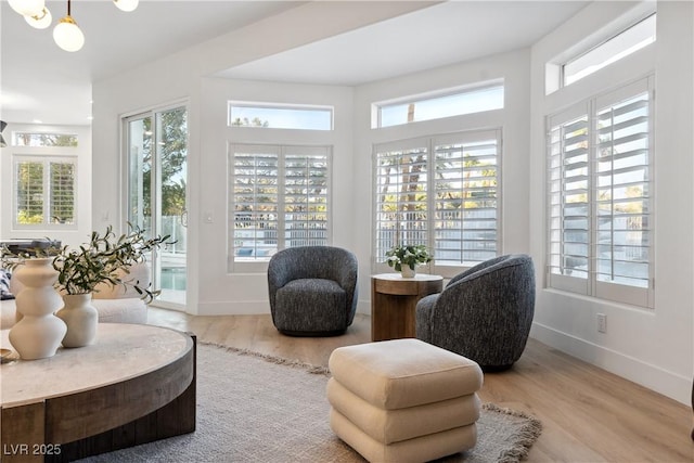 sitting room featuring baseboards, wood finished floors, and a healthy amount of sunlight
