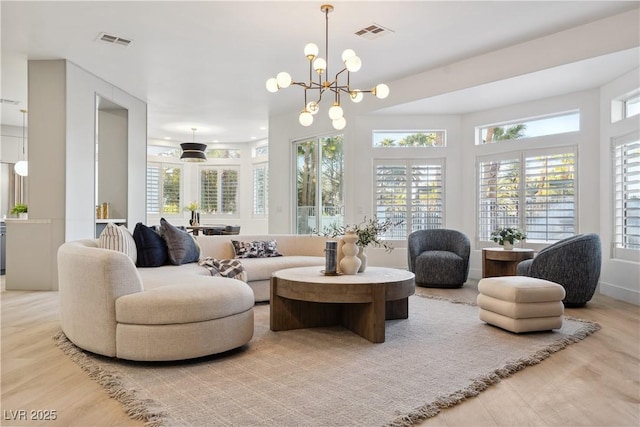 living area featuring a notable chandelier, visible vents, and wood finished floors