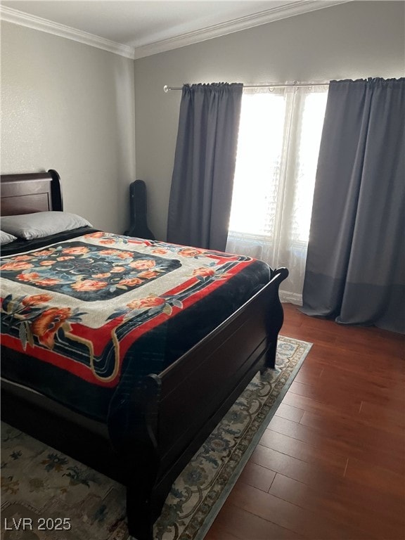 bedroom with ornamental molding and wood finished floors