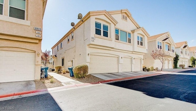 view of front facade featuring a residential view, driveway, a garage, and stucco siding