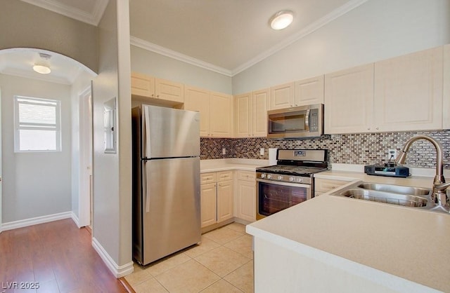 kitchen with light countertops, stainless steel appliances, backsplash, and a sink
