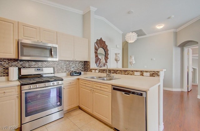 8811 Tomnitz Ave Unit 101, Las Vegas, NV 89178 - kitchen featuring appliances with stainless steel finishes, a sink, a peninsula, ornamental molding, and light countertops