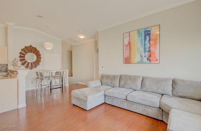 living room with lofted ceiling, light wood-style floors, baseboards, an inviting chandelier, and ornamental molding