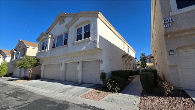 8811 Tomnitz Ave Unit 101, Las Vegas, NV 89178 - view of side of property featuring a garage, stucco siding, concrete driveway, and a residential view