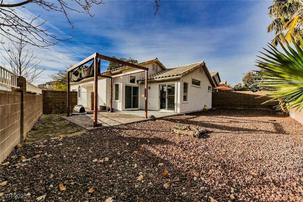 back of house featuring a tile roof, a patio, stucco siding, and a fenced backyard
