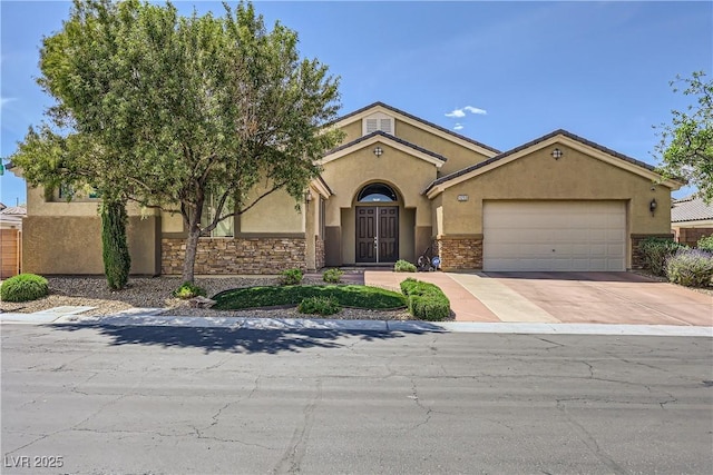 mediterranean / spanish house with stucco siding, concrete driveway, an attached garage, and stone siding