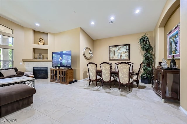 living room with a tile fireplace, visible vents, recessed lighting, and marble finish floor