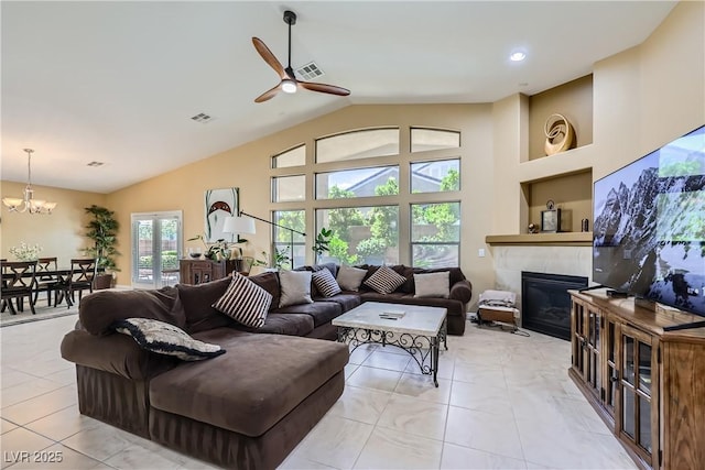living area with a tile fireplace, visible vents, high vaulted ceiling, and ceiling fan with notable chandelier