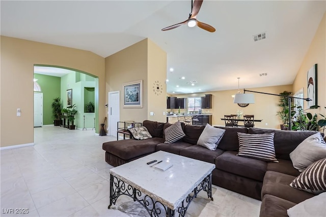 living area with arched walkways, ceiling fan, baseboards, visible vents, and lofted ceiling