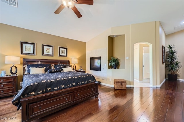 bedroom featuring arched walkways, hardwood / wood-style flooring, vaulted ceiling, baseboards, and visible vents