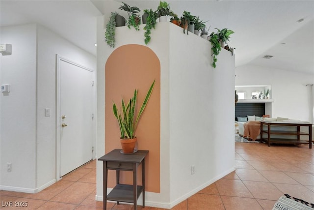 interior space with baseboards, visible vents, light tile patterned floors, and vaulted ceiling
