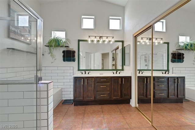 bathroom featuring a stall shower, double vanity, a sink, and tile patterned floors