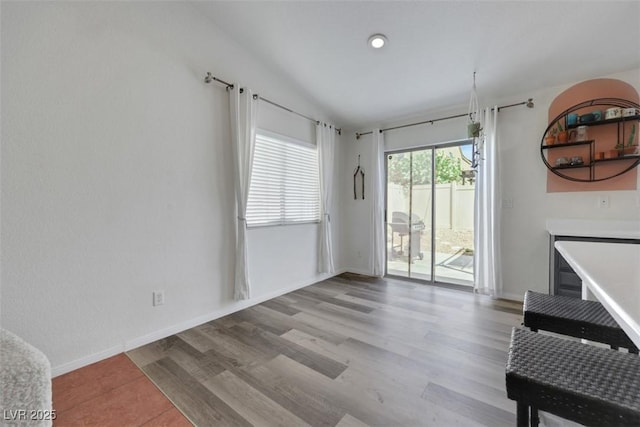 dining room featuring lofted ceiling, light wood-style floors, and baseboards