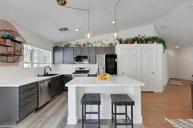 kitchen featuring a sink, appliances with stainless steel finishes, visible vents, a kitchen bar, and vaulted ceiling