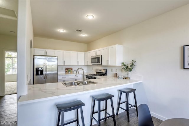 9966 Mystic Moss St, Las Vegas, NV 89183 - kitchen with white cabinetry, a sink, appliances with stainless steel finishes, dark wood-style flooring, and a peninsula