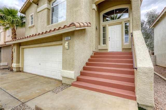 9966 Mystic Moss St, Las Vegas, NV 89183 - property entrance featuring an attached garage, driveway, stucco siding, and a tiled roof