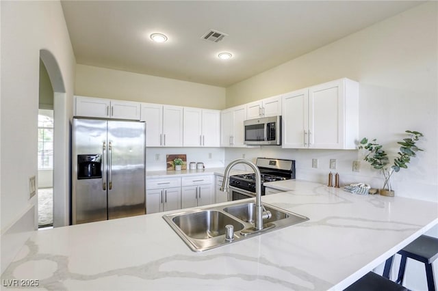 9966 Mystic Moss St, Las Vegas, NV 89183 - kitchen featuring visible vents, a peninsula, white cabinetry, arched walkways, and appliances with stainless steel finishes