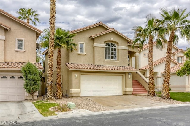 9966 Mystic Moss St, Las Vegas, NV 89183 - mediterranean / spanish house featuring concrete driveway, stairs, a tiled roof, an attached garage, and stucco siding
