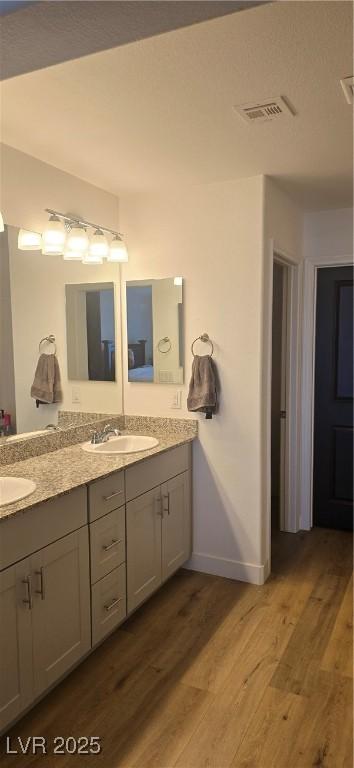 314 W Winston Ln, Indian Springs, NV 89018 - full bathroom with a sink, double vanity, visible vents, baseboards, and wood finished floors