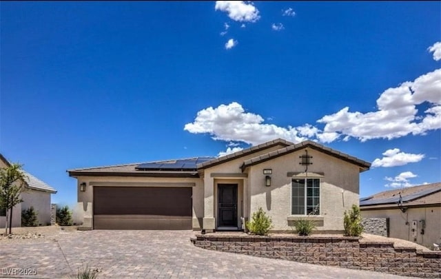314 W Winston Ln, Indian Springs, NV 89018 - view of front facade featuring stucco siding, roof mounted solar panels, decorative driveway, and an attached garage
