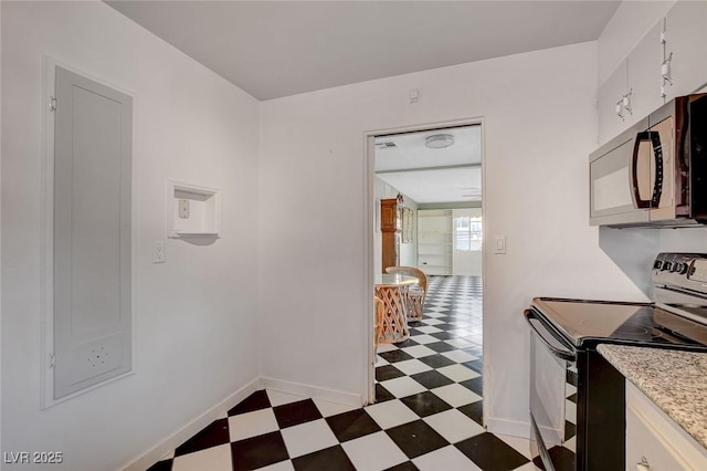 709 New Mexico St, Boulder City, NV 89005 - kitchen featuring baseboards, light floors, light stone counters, white cabinets, and black range with electric stovetop