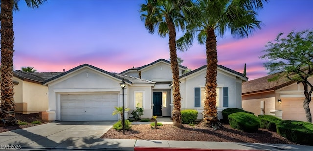ranch-style home with a garage, stucco siding, and concrete driveway