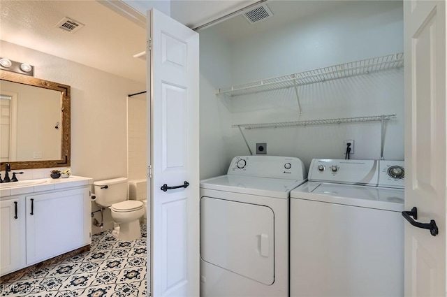 clothes washing area with visible vents, washing machine and clothes dryer, laundry area, and a sink