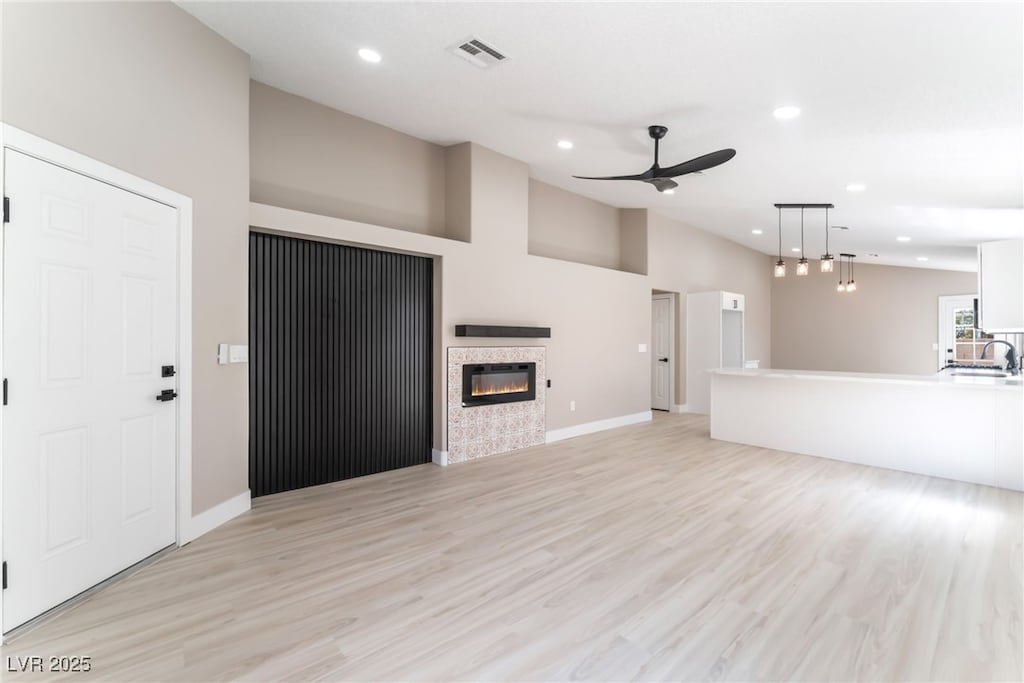 unfurnished living room featuring visible vents, a glass covered fireplace, recessed lighting, light wood-type flooring, and a ceiling fan