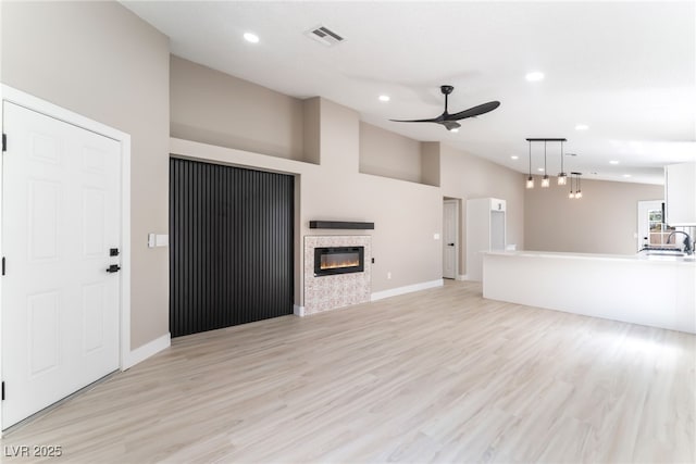 unfurnished living room featuring visible vents, a glass covered fireplace, recessed lighting, light wood-type flooring, and a ceiling fan