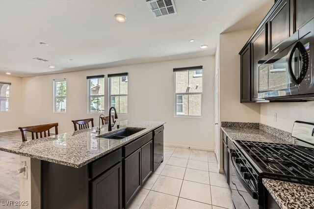 2862 Starling Summit St, Henderson, NV 89044 - kitchen with black appliances, a sink, light stone countertops, a kitchen island with sink, and baseboards