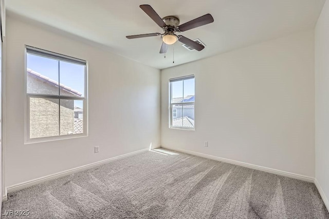 carpeted spare room featuring baseboards and ceiling fan