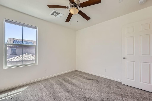 spare room featuring carpet floors, a ceiling fan, a smoke detector, and baseboards