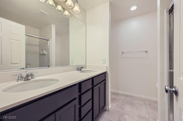 bathroom with a shower stall, double vanity, baseboards, and tile patterned flooring
