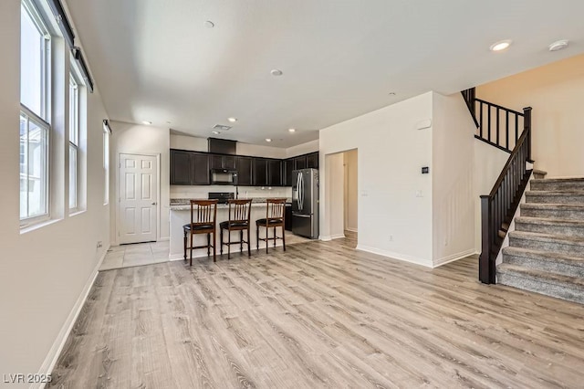 living area with baseboards, light wood finished floors, stairs, and recessed lighting