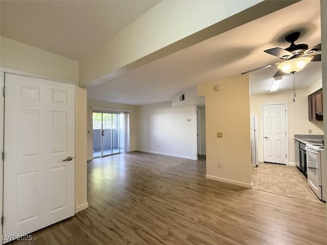 unfurnished living room featuring baseboards, wood finished floors, and a ceiling fan