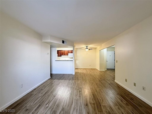 unfurnished living room with visible vents, ceiling fan, baseboards, and dark wood finished floors
